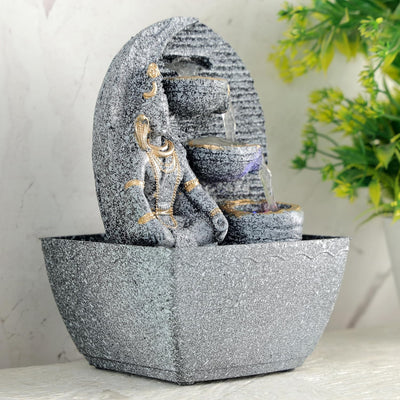 A small, tabletop fountain made of polyresin, a durable and lightweight material. Water flows through the fountain, creating a soothing sound. The fountain may have additional decorative elements, such as rocks, plants, or a figurine.