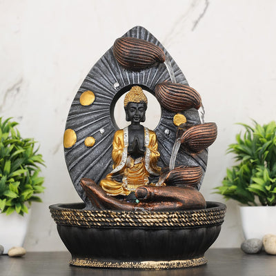 A Hindu-inspired water fountain featuring statues of various Hindu gods, including Buddha, surrounded by cascading waterfalls and lush greenery. The fountain is likely made of stone or marble and has a traditional Indian design.