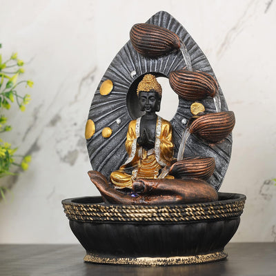 A Hindu-inspired water fountain featuring statues of various Hindu gods, including Buddha, surrounded by cascading waterfalls and lush greenery. The fountain is likely made of stone or marble and has a traditional Indian design.