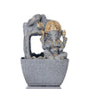 A water fountain featuring a statue of Lord Ganesha, the Hindu god of wisdom and remover of obstacles. Water flows around or from the statue, creating a serene and calming atmosphere. The fountain may be made of stone, marble, or other materials and may have additional decorative elements, such as plants or lights