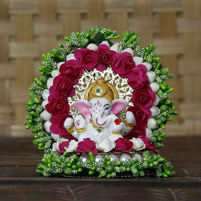 A small golden idol of Lord Ganesha, the Hindu god of wisdom and remover of obstacles, placed on a car dashboard.