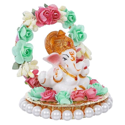  A small golden idol of Lord Ganesha, the Hindu god of wisdom and remover of obstacles, placed on a car dashboard