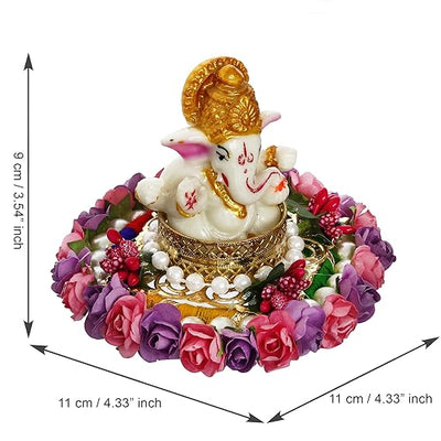  A Hindu god, Lord Ganesha, idol placed on a decorative plate with purple and pink floral designs, suitable for home decor.