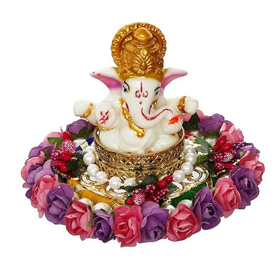  A Hindu god, Lord Ganesha, idol placed on a decorative plate with purple and pink floral designs, suitable for home decor.