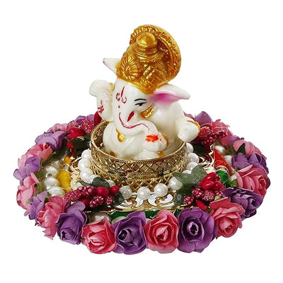  A Hindu god, Lord Ganesha, idol placed on a decorative plate with purple and pink floral designs, suitable for home decor.