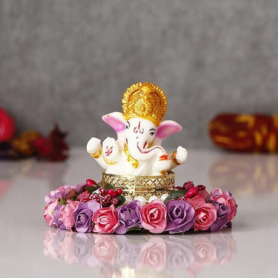  A Hindu god, Lord Ganesha, idol placed on a decorative plate with purple and pink floral designs, suitable for home decor.