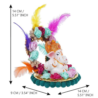 A small golden idol of Lord Ganesha, the Hindu god of wisdom and remover of obstacles, seated on a throne made of colorful flowers. The idol is placed on a car dashboard.