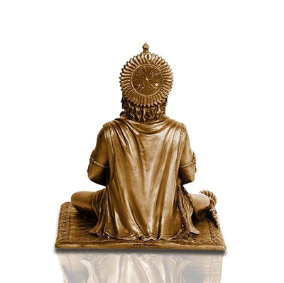 A small golden idol of Lord Hanuman, the Hindu monkey god, seated on a throne made of colorful flowers. The idol is placed on a car dashboard.