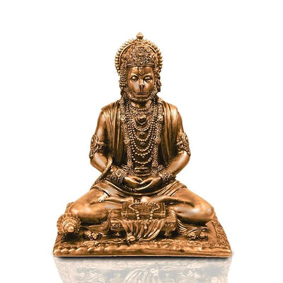 A small golden idol of Lord Hanuman, the Hindu monkey god, seated on a throne made of colorful flowers. The idol is placed on a car dashboard.