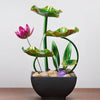 A table-top fountain featuring a lotus pond with water gently flowing around and over the lotus flowers.