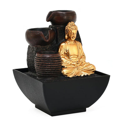 A water fountain featuring a statue of Buddha seated in meditation pose. Water flows from the Buddha's hands or from a nearby source, creating a serene and calming atmosphere. The fountain may be made of stone, marble, or other materials and may have additional decorative elements.