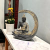 A decorative statue of Buddha seated in meditation pose under a crescent moon. The statue may be made of marble, stone, or another material and may have a serene and calming expression.