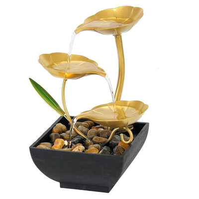 A small, tabletop fountain made of metal. Water flows through the metal pipes or channels, creating a soothing sound. The fountain may have additional decorative elements, such as rocks, plants, or a figurine.