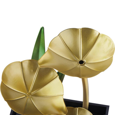 A small, tabletop fountain made of metal. Water flows through the metal pipes or channels, creating a soothing sound. The fountain may have additional decorative elements, such as rocks, plants, or a figurine.