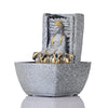 A water fountain featuring a statue of Lord Buddha, the founder of Buddhism, surrounded by cascading waterfalls or a serene pool of water. The fountain may be made of stone, marble, or other materials and may have additional decorative elements, such as plants or lights.