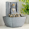 A water fountain featuring a statue of Lord Buddha, the founder of Buddhism, surrounded by cascading waterfalls or a serene pool of water. The fountain may be made of stone, marble, or other materials and may have additional decorative elements, such as plants or lights.