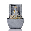 A water fountain featuring a statue of Lord Buddha, the founder of Buddhism, surrounded by cascading waterfalls or a serene pool of water. The fountain may be made of stone, marble, or other materials and may have additional decorative elements, such as plants or lights.