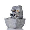 A small, tabletop fountain made of polyresin, a durable and lightweight material, featuring a statue of Lord Ganesha, the Hindu god of wisdom and remover of obstacles. Water flows around or from the statue, creating a serene and calming atmosphere. The fountain may have additional decorative elements, such as plants or lights.