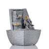 A small, tabletop fountain made of polyresin, a durable and lightweight material, featuring a statue of Lord Ganesha, the Hindu god of wisdom and remover of obstacles. Water flows around or from the statue, creating a serene and calming atmosphere. The fountain may have additional decorative elements, such as plants or lights.