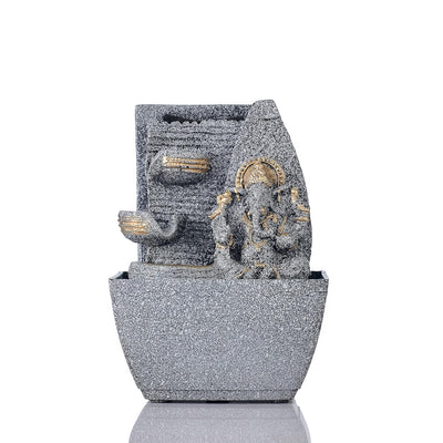 A small, tabletop fountain made of polyresin, a durable and lightweight material, featuring a statue of Lord Ganesha, the Hindu god of wisdom and remover of obstacles. Water flows around or from the statue, creating a serene and calming atmosphere. The fountain may have additional decorative elements, such as plants or lights.