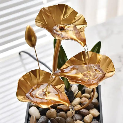 A three-tiered tabletop fountain featuring cascading waterfalls and a decorative base. The fountain may be made of ceramic, stone, or other materials and may have additional decorative elements, such as plants or lights.