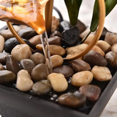 A three-tiered tabletop fountain featuring cascading waterfalls and a decorative base. The fountain may be made of ceramic, stone, or other materials and may have additional decorative elements, such as plants or lights.