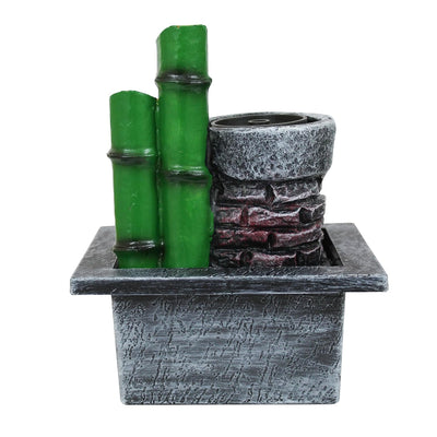 A small, tabletop water fountain made of bamboo. Water flows through the bamboo pipes, creating a soothing sound. The fountain may have additional decorative elements, such as rocks or plants.