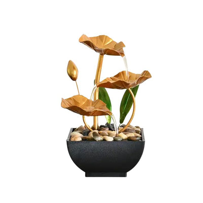A small, tabletop fountain featuring a lotus flower design. Water flows from the lotus petals or from a nearby source, creating a serene and calming atmosphere. The fountain may be made of ceramic, stone, or other materials and may have additional decorative elements.