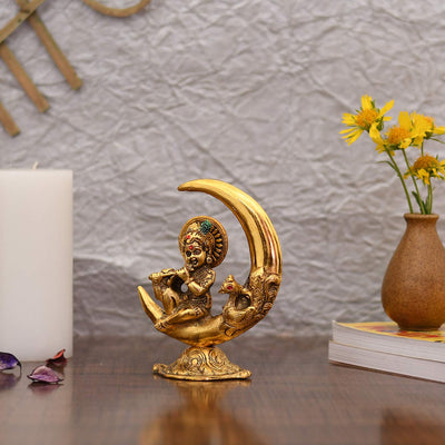 Handcrafted metal statue of Baby Krishna playing the flute, featuring a gold finish, representing joy and divine playfulness.