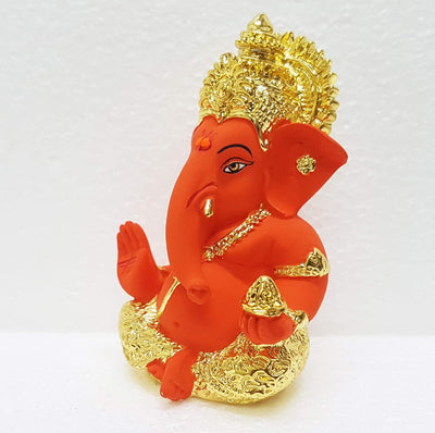 Handcrafted ceramic Ganesha idol with gold and sindoor orange finish, symbolizing prosperity and wisdom, ideal for altars and home decor.