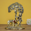 Intricate Lord Krishna showpiece in metal, depicting the deity playing the flute under a tree, surrounded by a golden cow and calf.