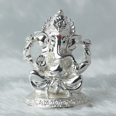 A beautifully crafted handmade Ganesha idol made of resin, showcasing intricate details and vibrant colors. The idol, symbolizing prosperity and wisdom, is positioned on a decorative altar surrounded by floral arrangements, representing its spiritual significance in Hinduism.