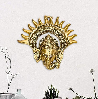 Handmade metal Ganesha wall sculpture with a leaf-shaped design, gold finish, 17.78x17.78 cm, 300g. Ideal for home decor and inviting prosperity and wisdom.