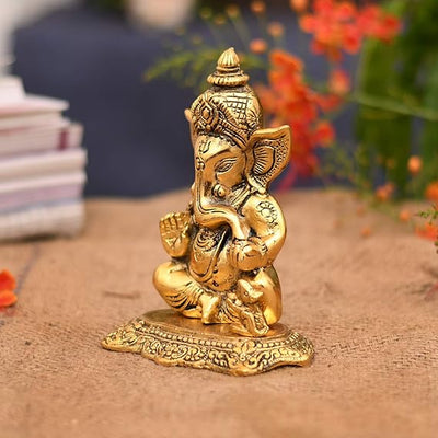 A small golden idol of Lord Ganesha, the Hindu god of wisdom and remover of obstacles, suitable for home decor.